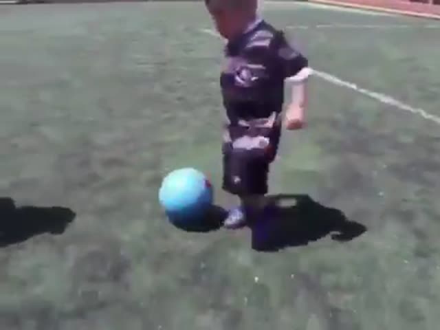 Юный мальчуган прекрасно владеет футбольным мячом
