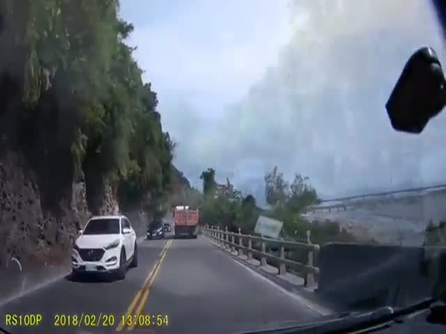 Падение крупного камня перед машиной на горной дороге