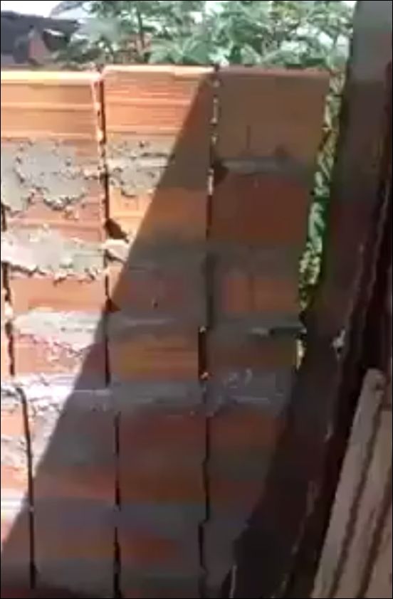 Женщина пытается построить забор возле своего дома