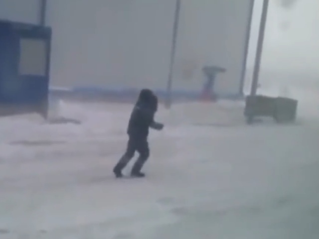 Мужчина пытается противостоять холодному ветру в поселке Сабетта ЯНАО