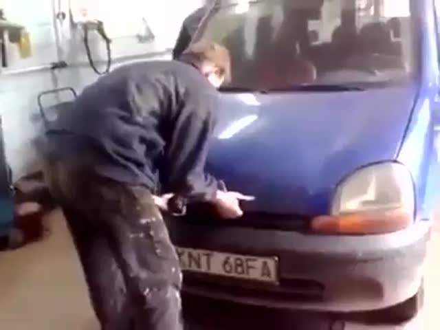 Работник СТО пытается открыть капот автомобиля