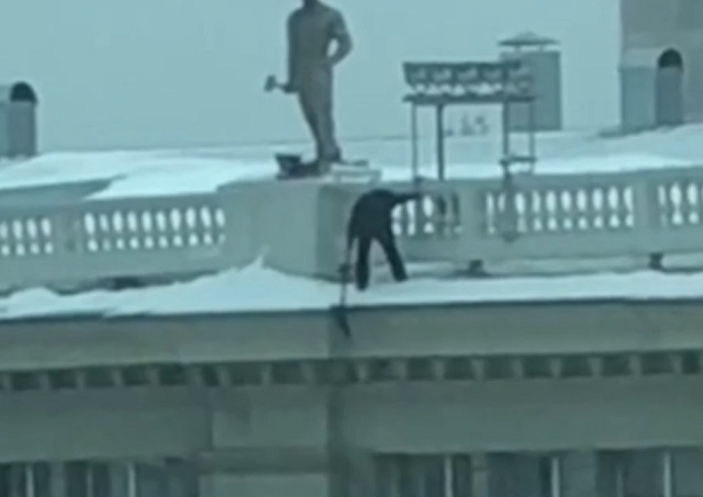 Мужчина сбивает сосульки с крыши без страховки