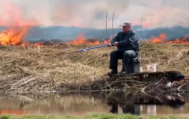 Рыбак не обращает внимания на пожар и продолжает заниматься любимым делом
